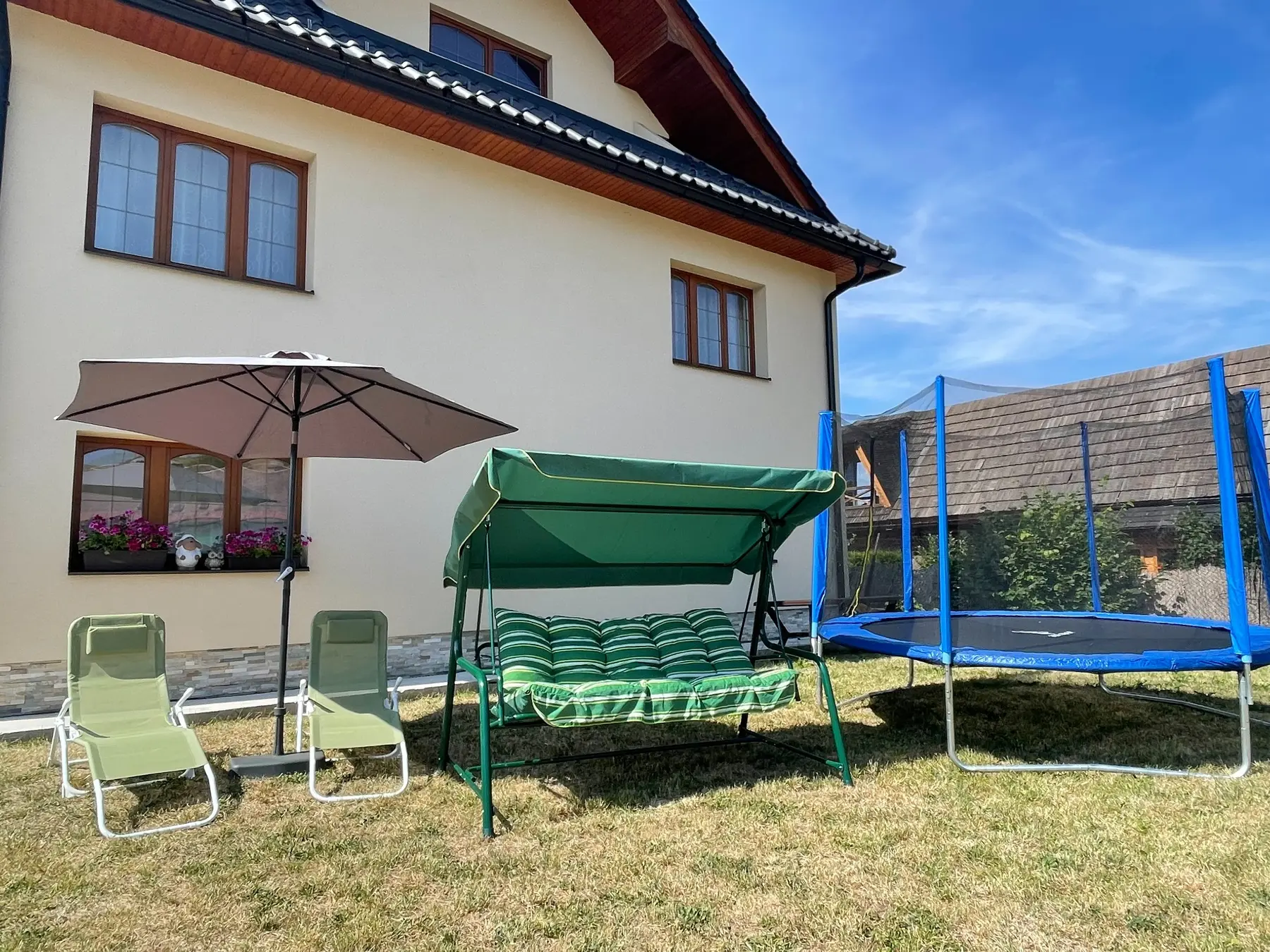 Priestranná záhrada s trampolínou.
